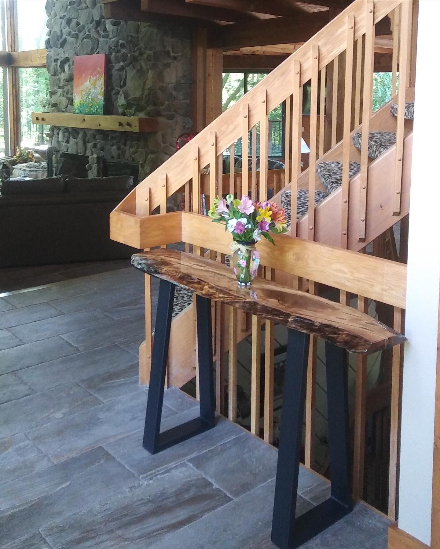 Wooden staircase with a small table and vase of flowers in a rustic home interior