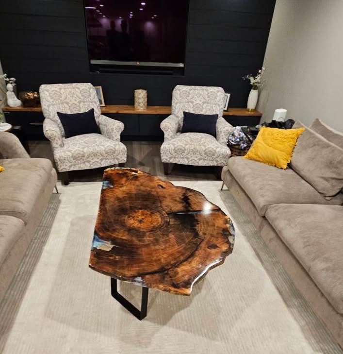 Modern living room with beige sofas, patterned chairs, and a live-edge wood coffee table