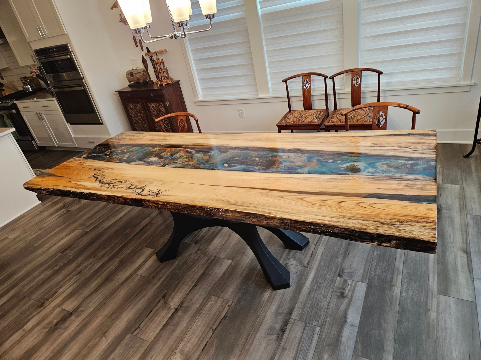 Rustic live-edge dining table with black metal base in a bright kitchen-dining room