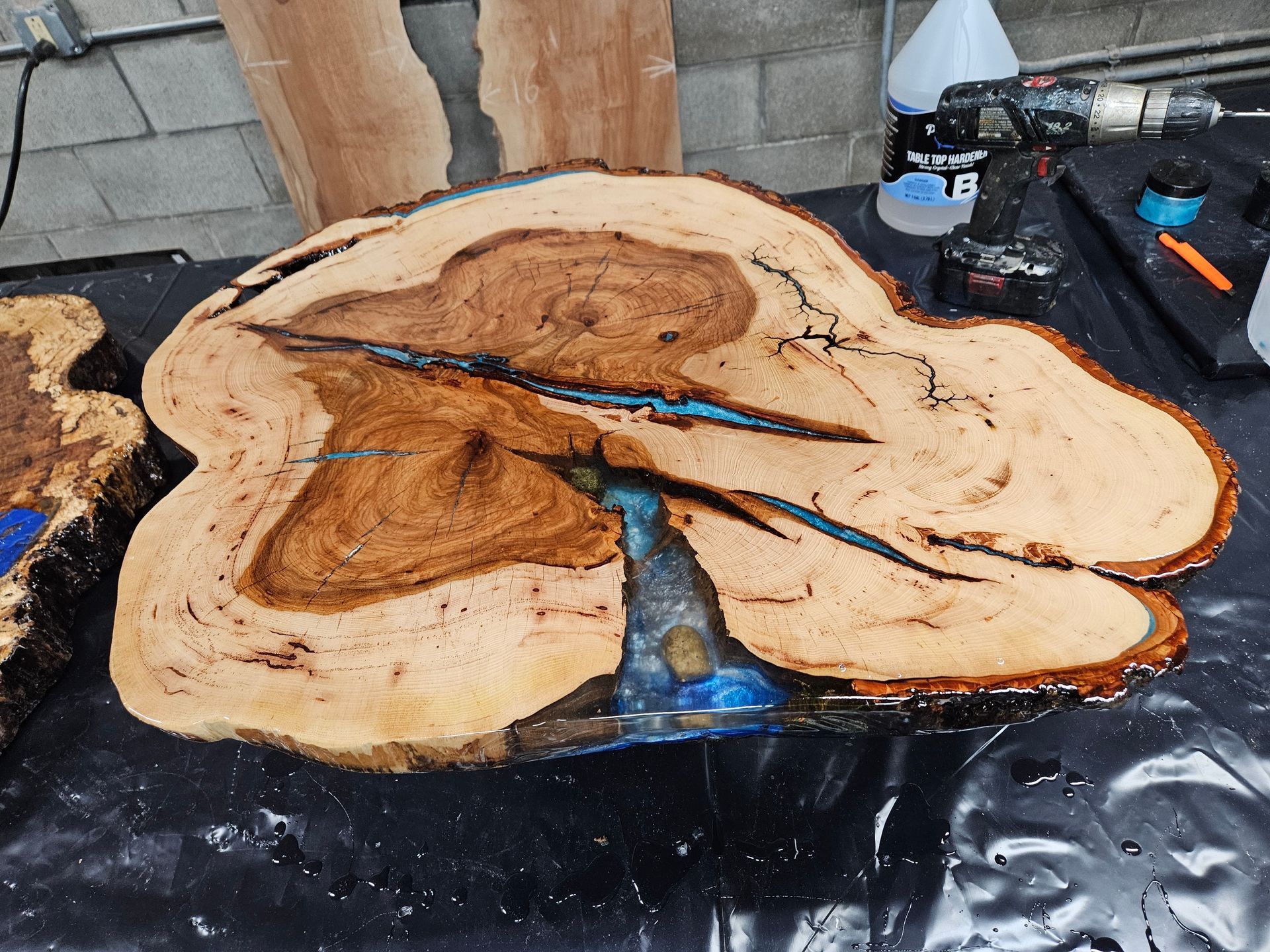 Wood slice with blue resin river in a black workbench setting