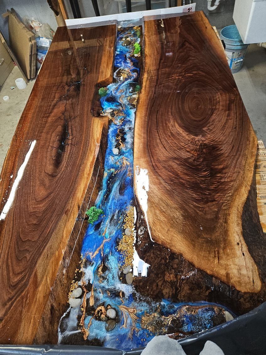Wooden resin table with blue and gold river-like epoxy inlay on a workbench