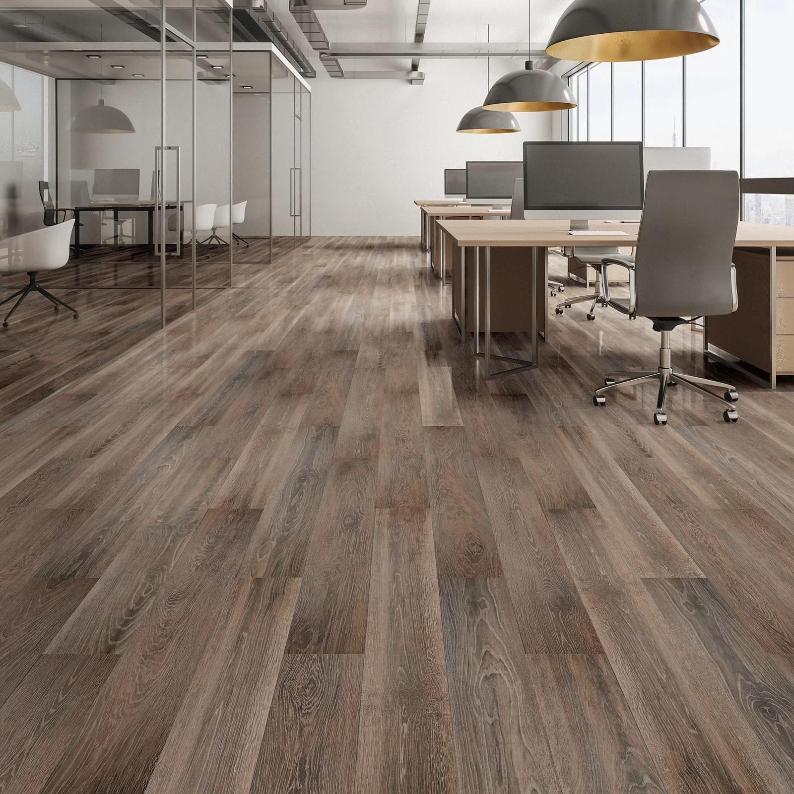 Modern open office with wood flooring, desks, office chairs, and pendant lights.