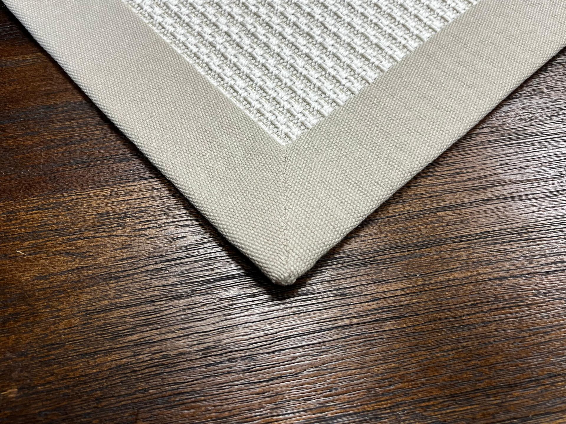 Beige woven placemat corner on a dark wood tabletop