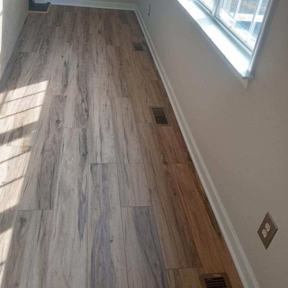 Empty room with wood-look flooring, white walls, a window, and floor vents along the side.