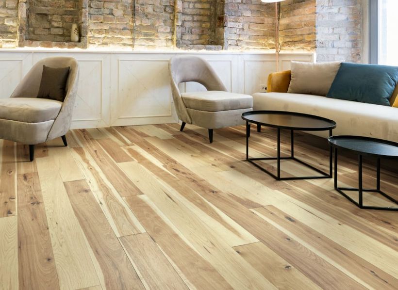 Modern living room with light wood floors, beige and blue chairs, curved white sofa, and black coffee tables.