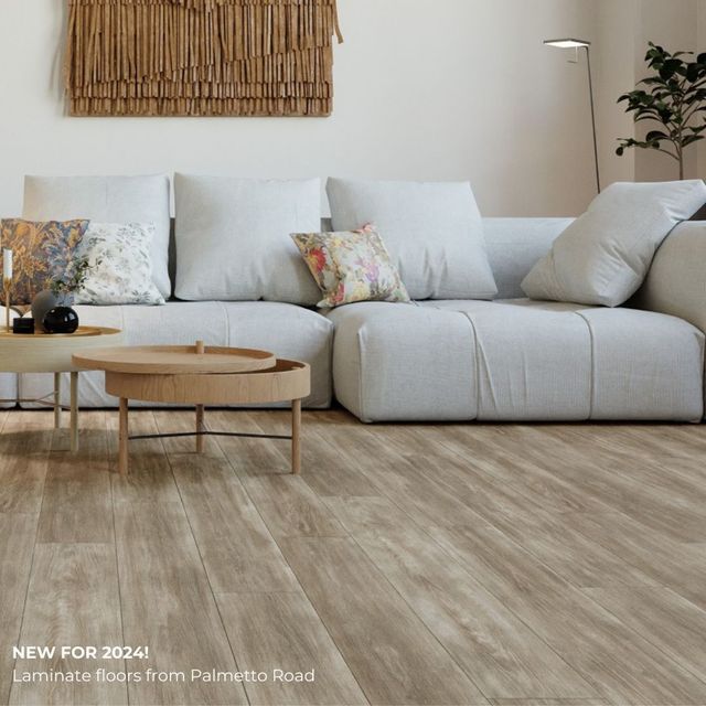 Modern living room with a white sectional sofa, wooden coffee table, wall art, and indoor plant on light wood flooring