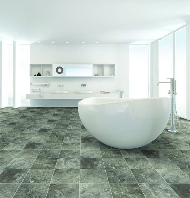 Modern white bathroom with a freestanding tub, dark stone floor, and bright minimalist cabinetry.