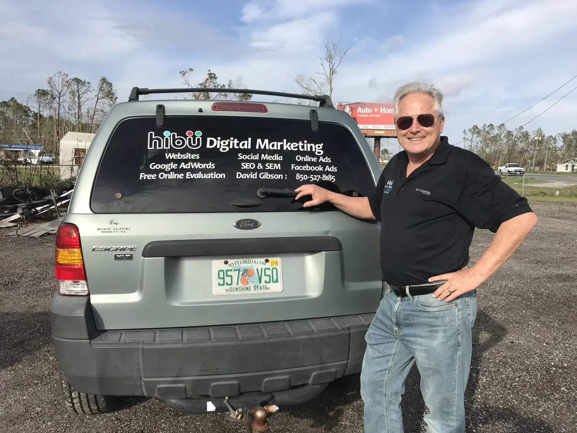 A man is standing in front of a car that says digital marketing on the back window.