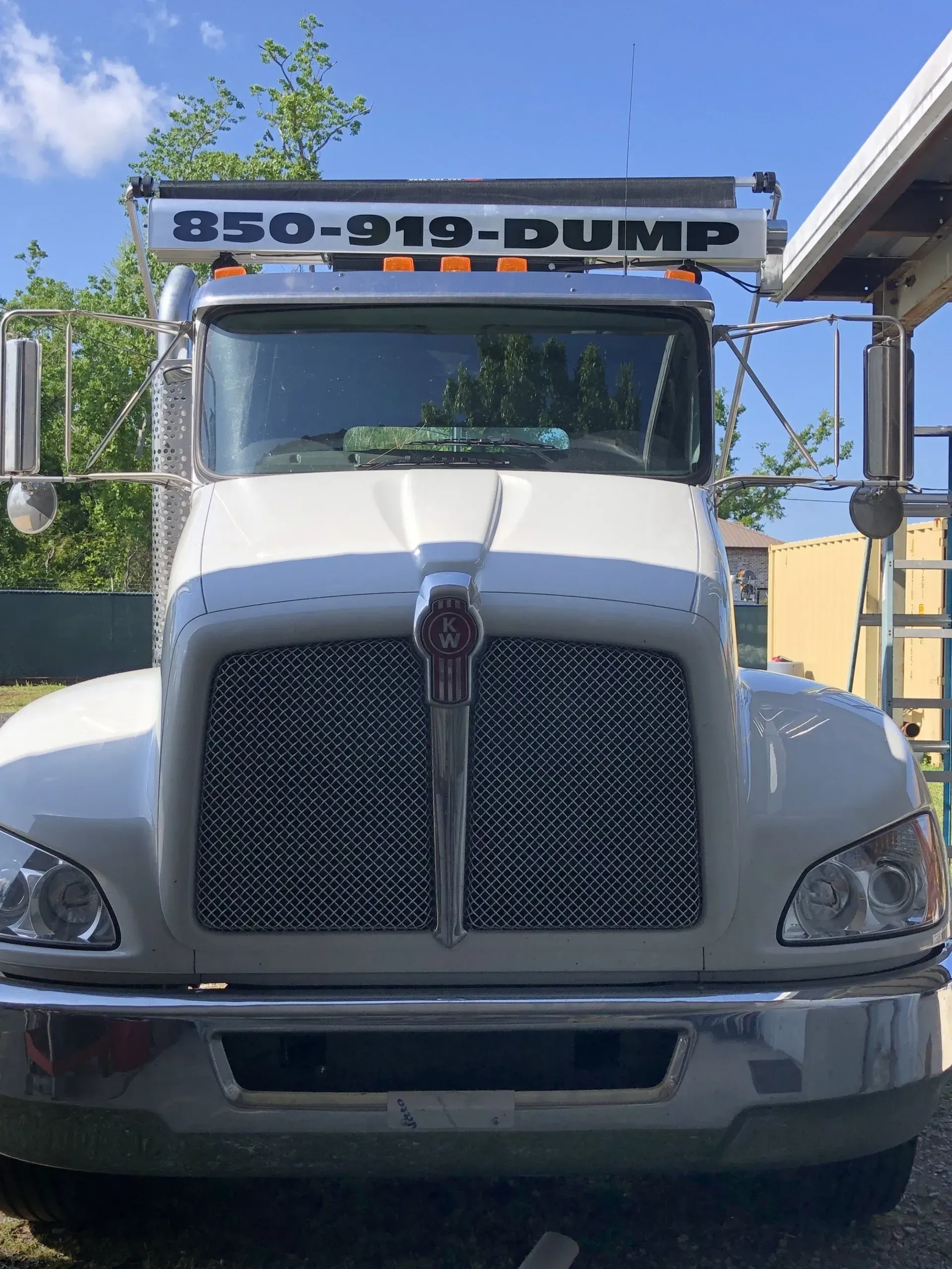 A white dump truck is parked in front of a building