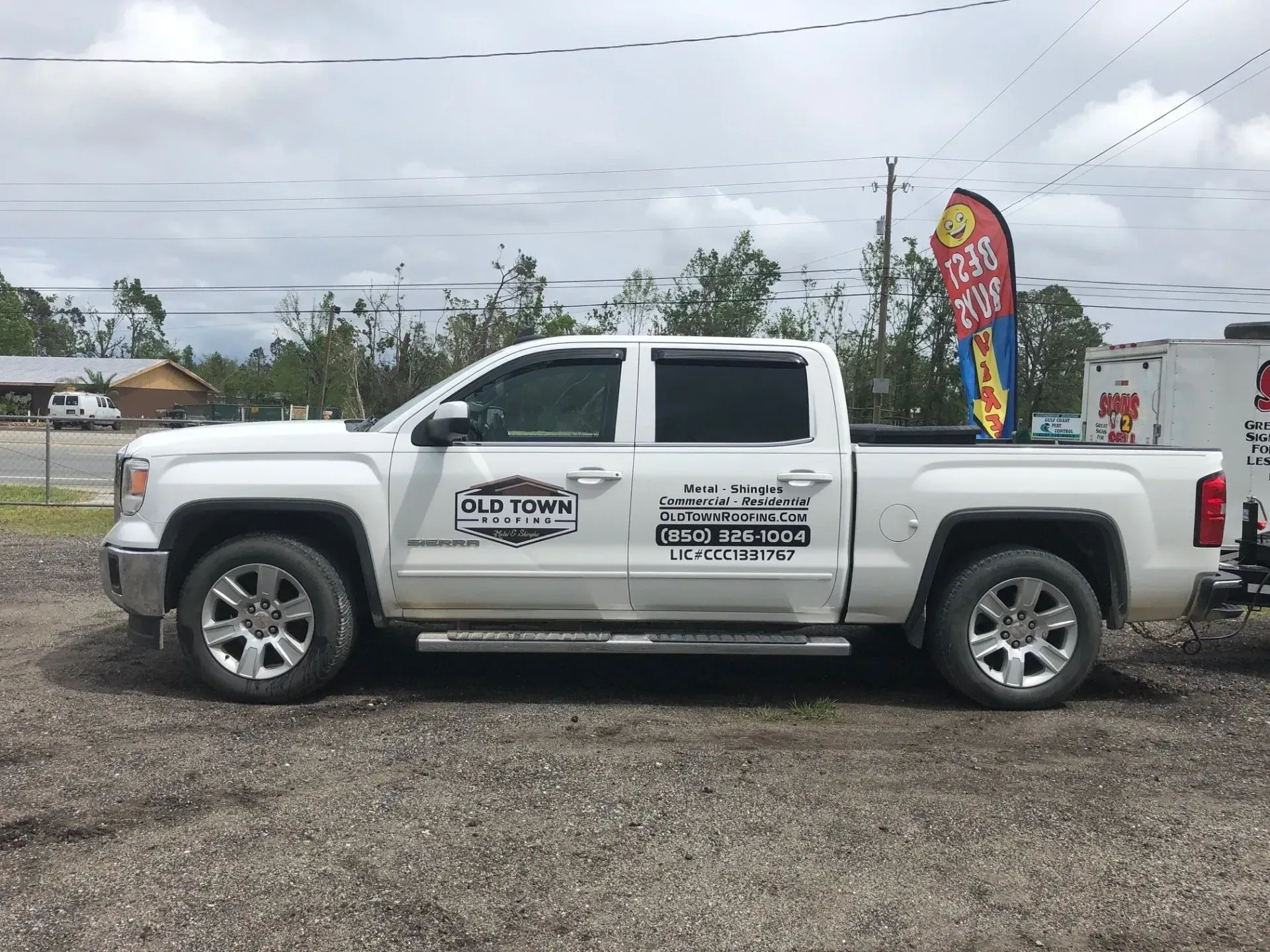 A white pickup truck is parked in a gravel lot.