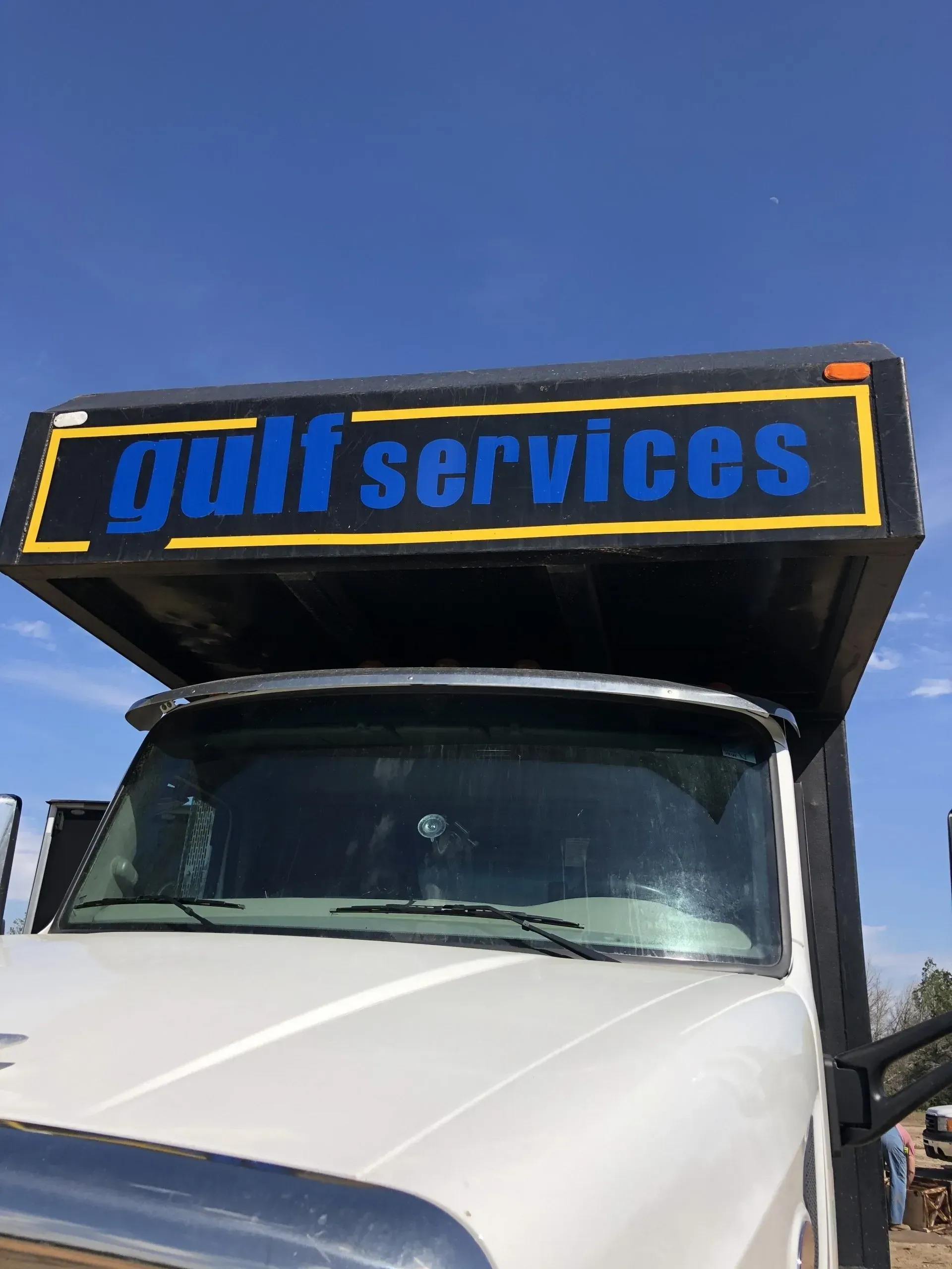 A white truck with a blue sign that says gulf services