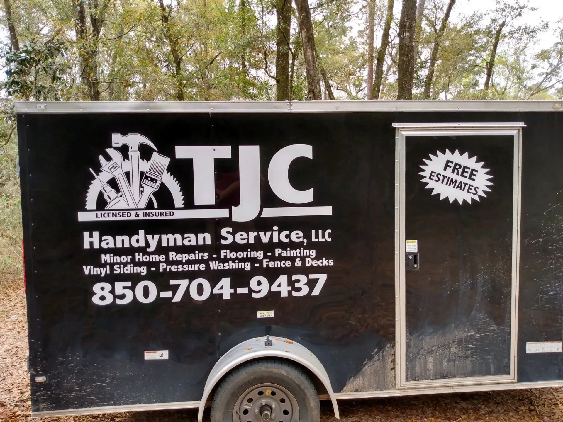 A handyman service trailer is parked in the woods