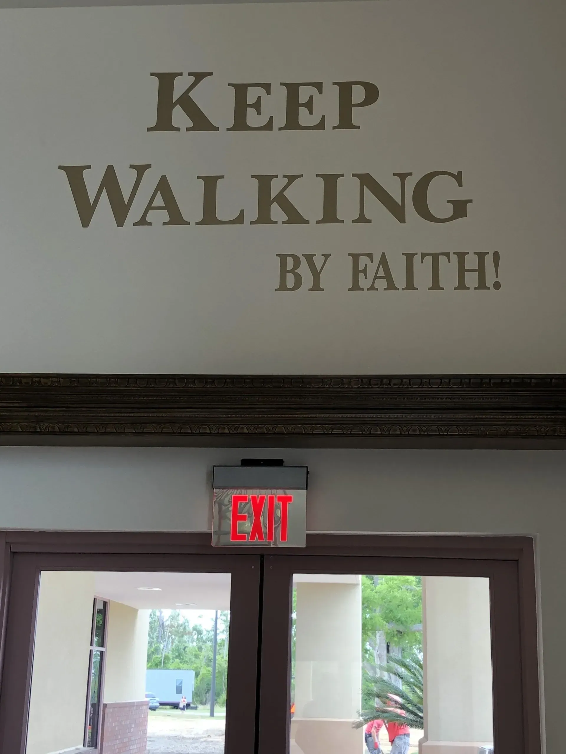 A sign on a wall that says keep walking by faith