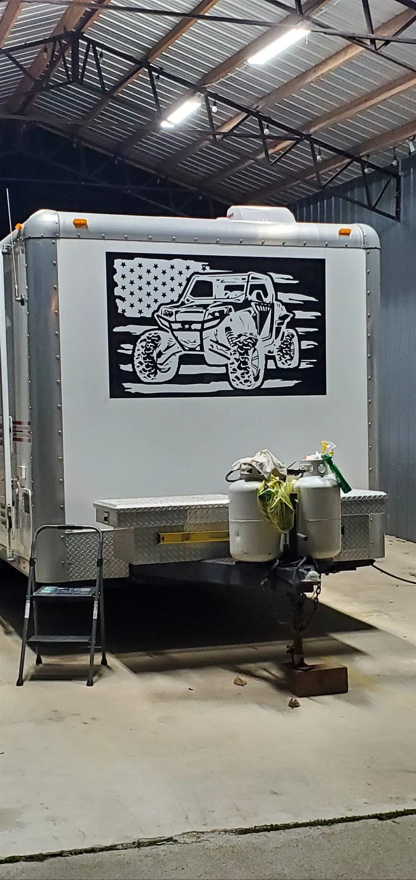 A trailer with a picture of a motorcycle on the side is parked in a garage.