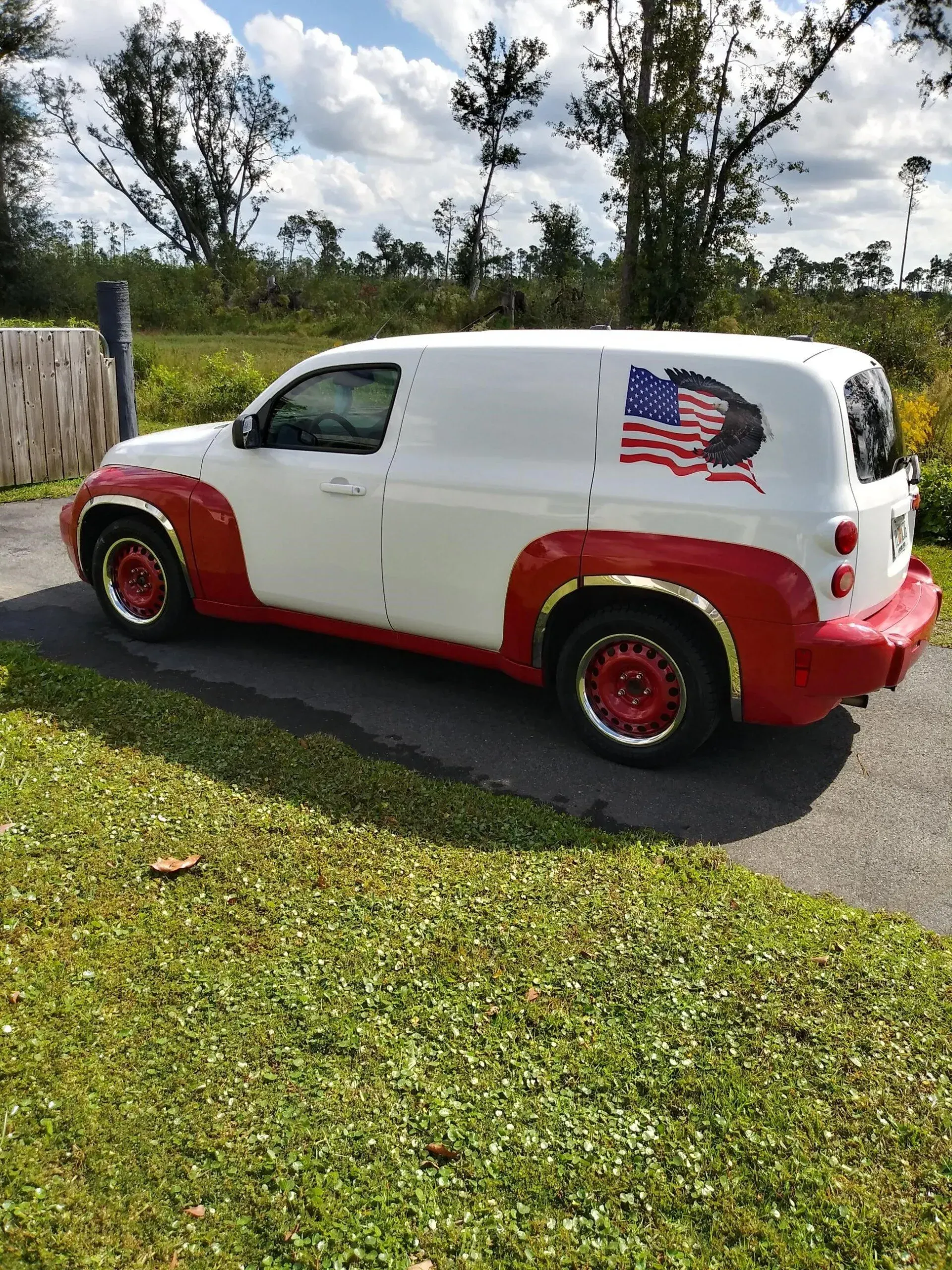 A white and red van with an american flag on the side is parked on the side of the road.