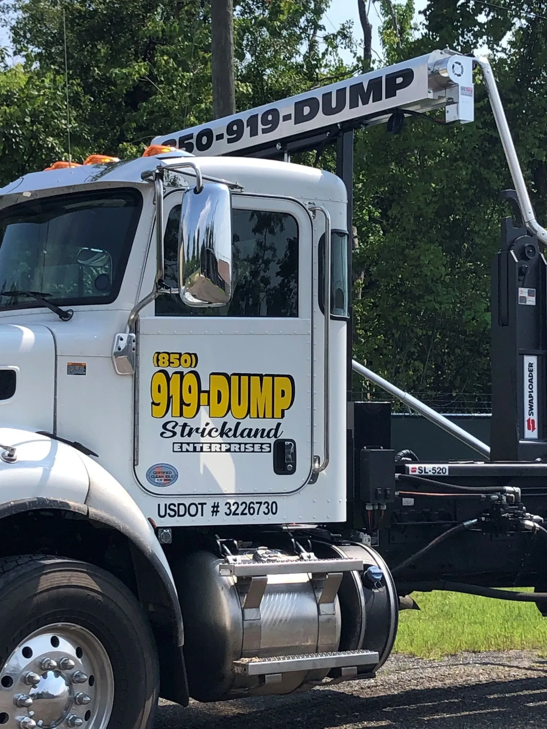 A white dump truck is parked on the side of the road.