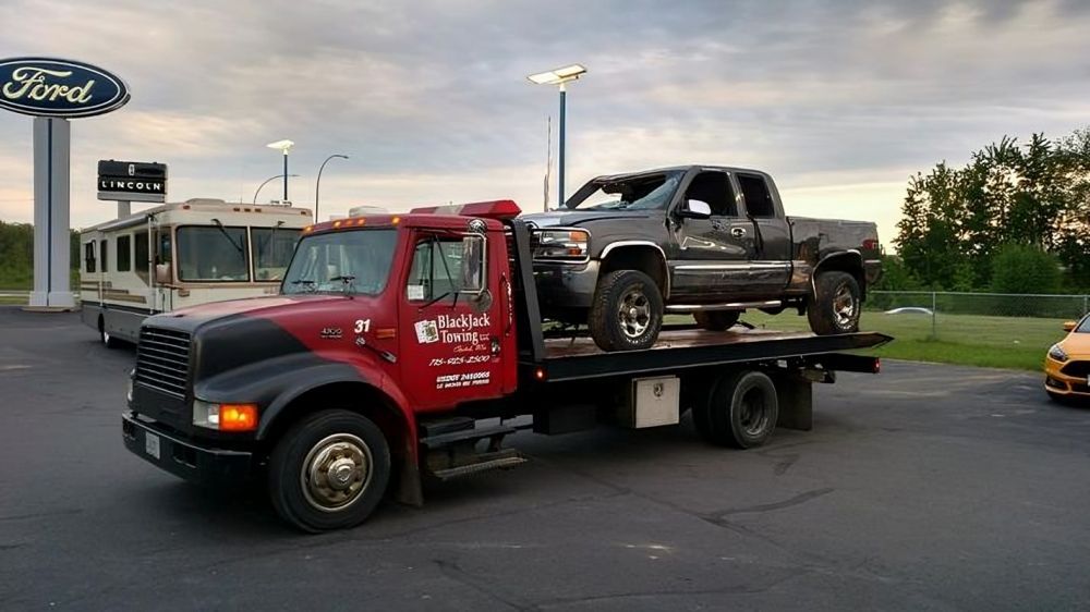 A silver car is being towed by a white truck. A silver car is being towed by a white truck.