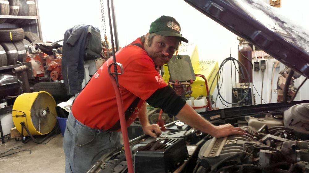 A man is working on the engine of a car in a garage.