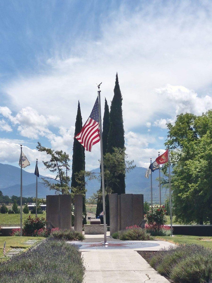 An american flag is flying in front of a cemetery