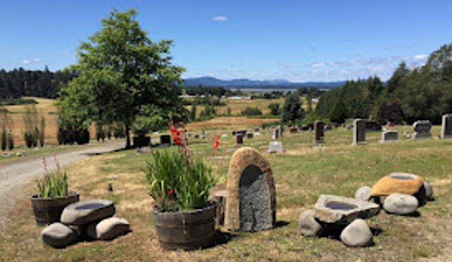 A cemetery with a lot of rocks and plants in the grass.