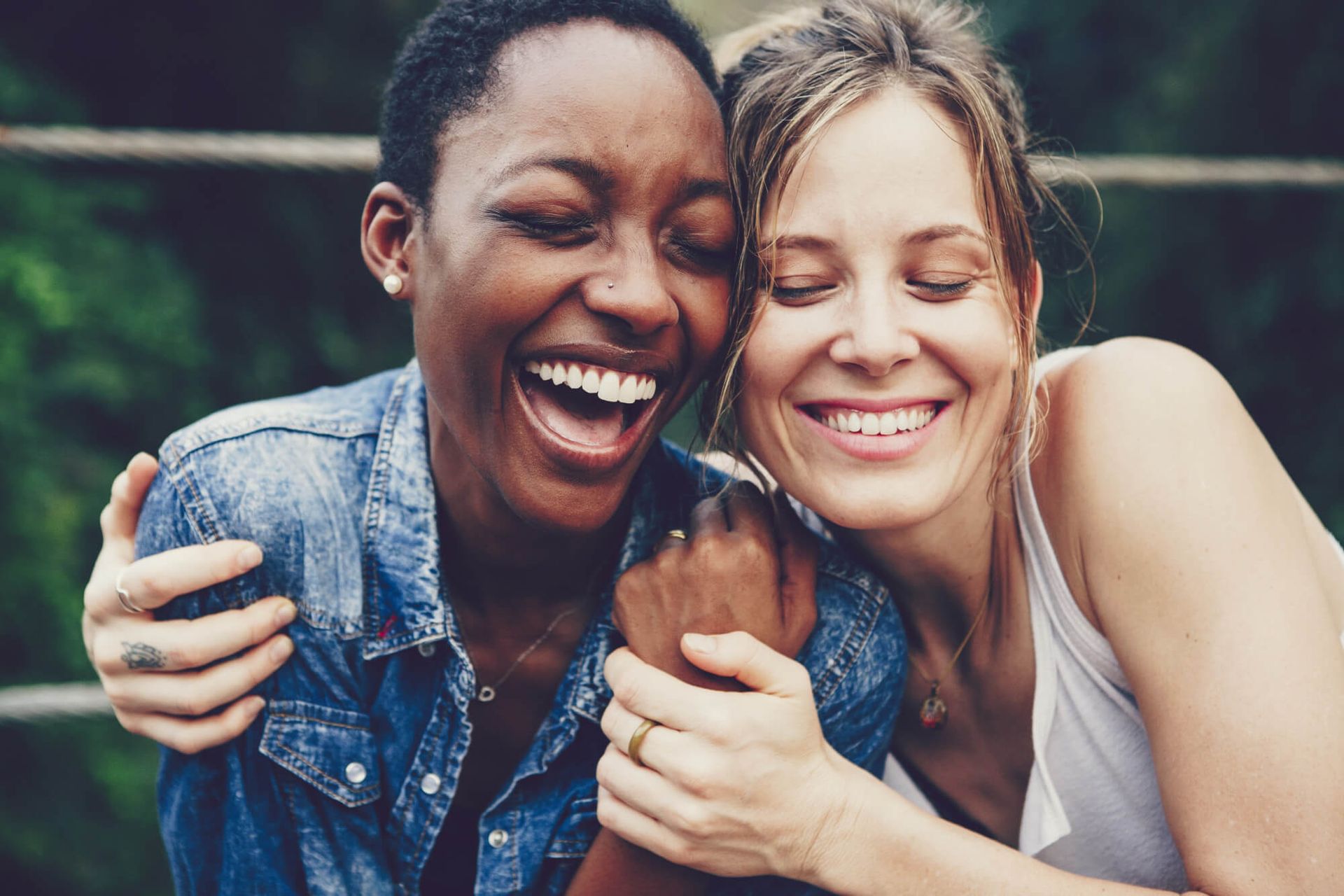 Two women are hugging each other and laughing.