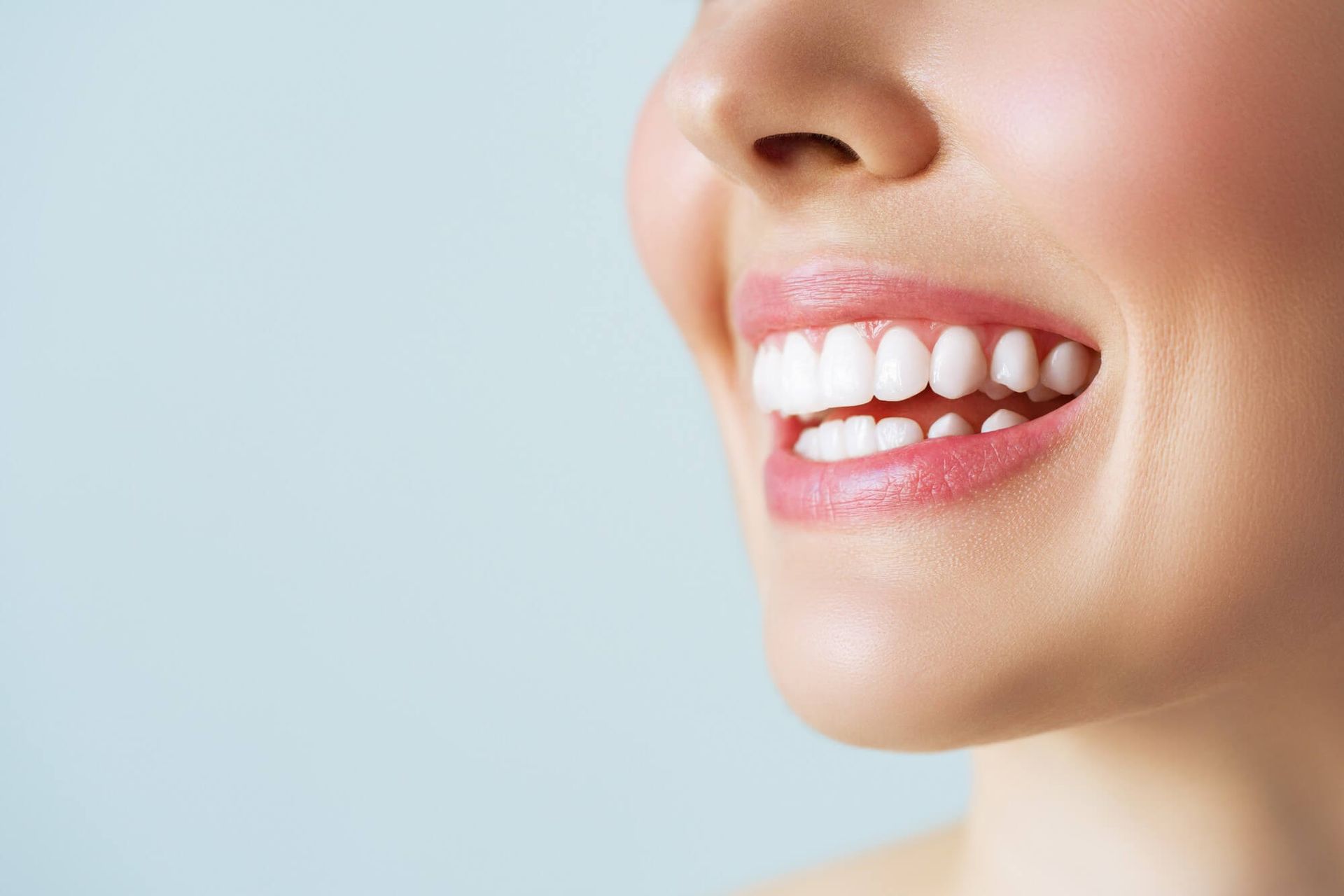 A close up of a woman 's smile with white teeth and pink lips.