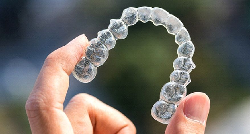 A person is holding a clear brace in their hand.
