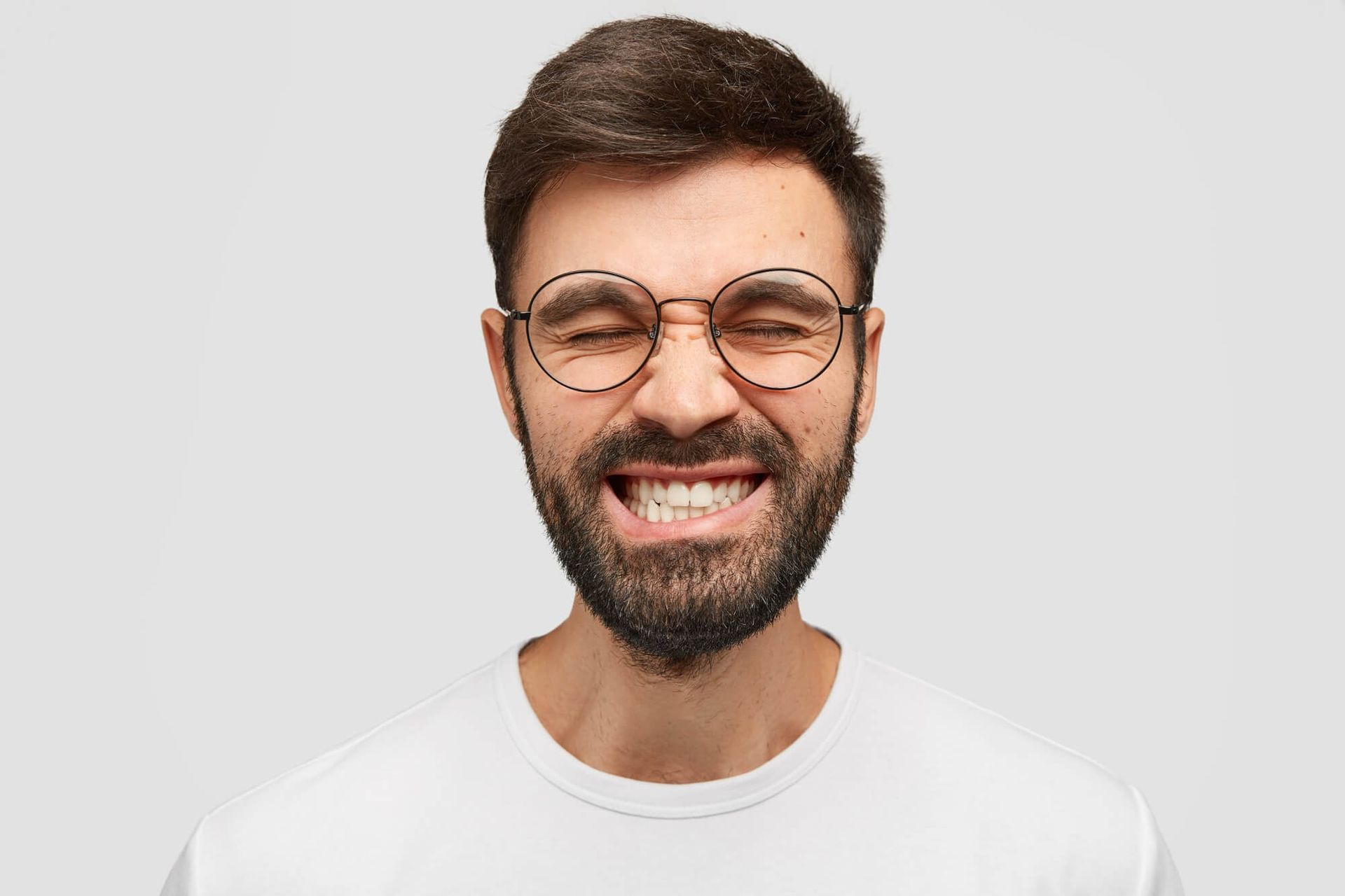 A man with a beard and glasses is making a funny face.