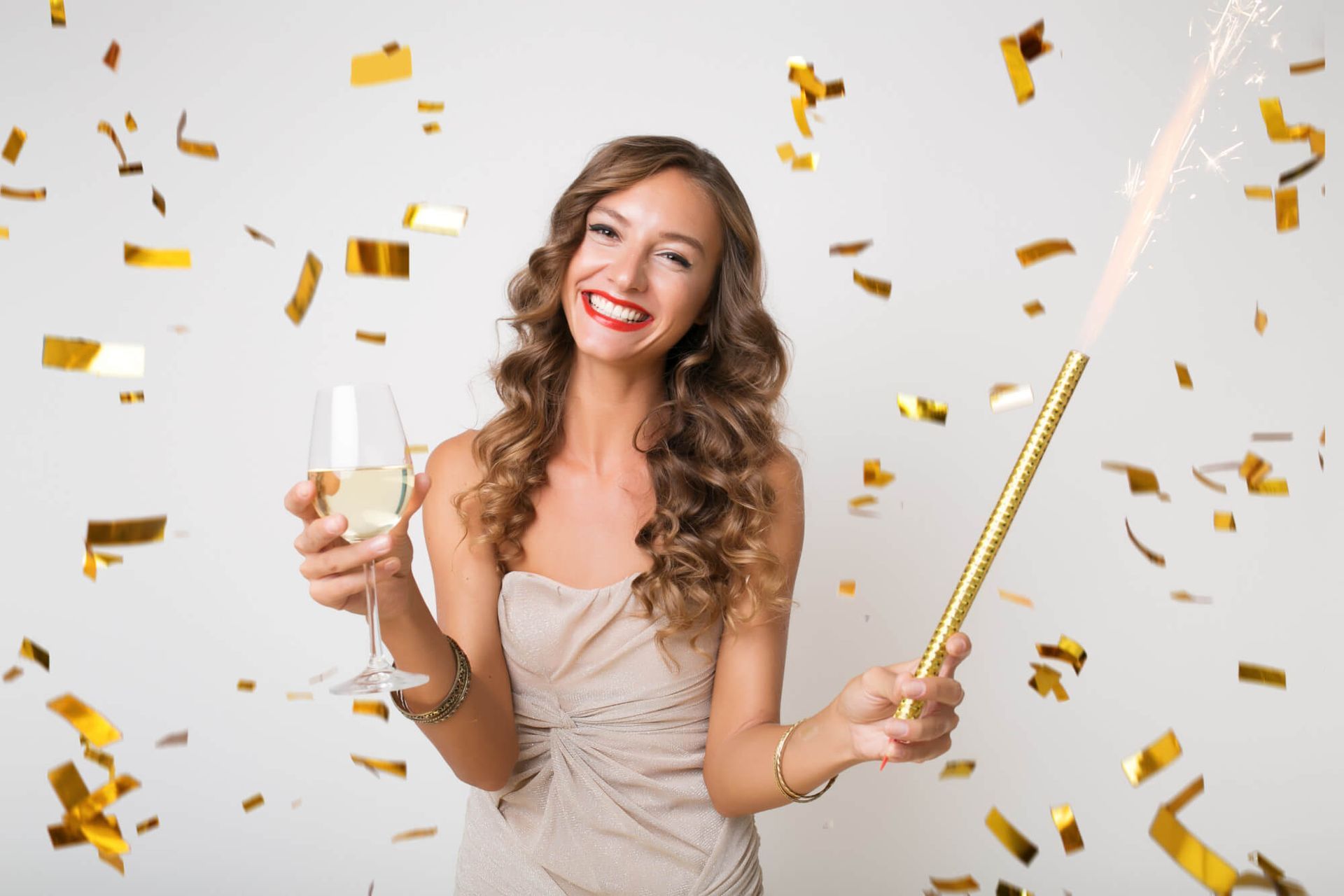 A woman is holding a glass of champagne and a sparkler.