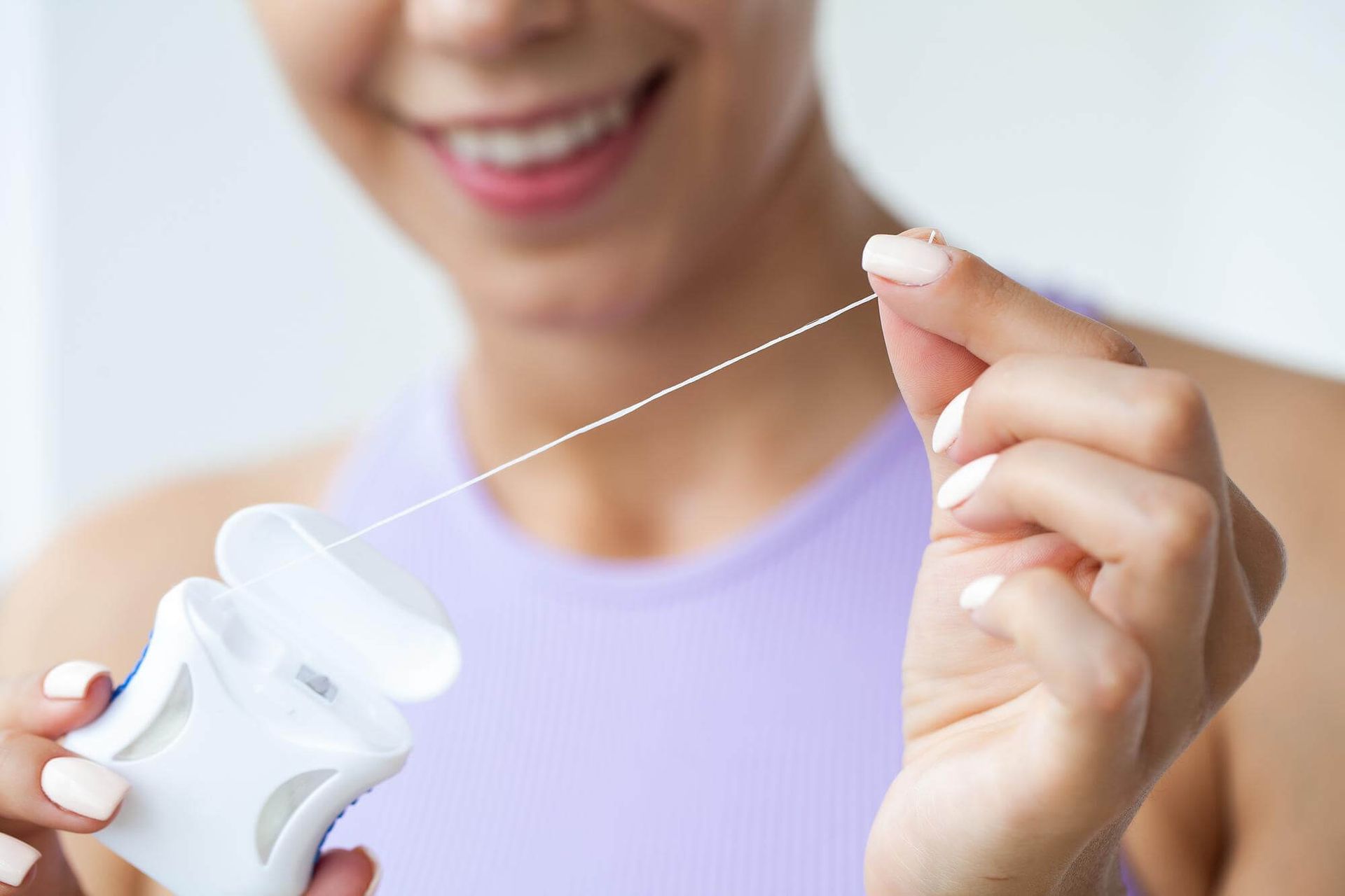 A woman is holding a bottle of floss in her hands.