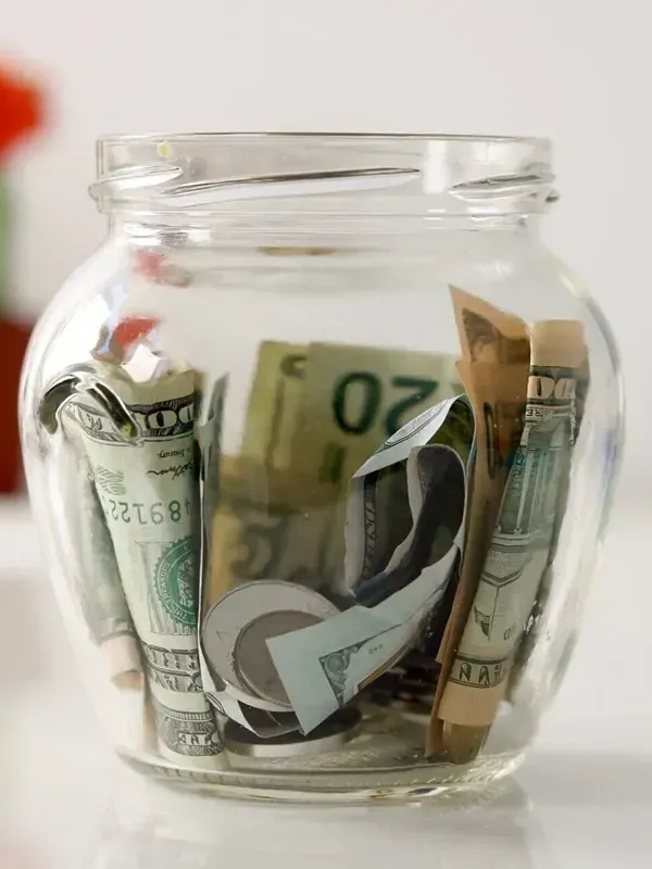 A glass jar filled with dollar bills and coins