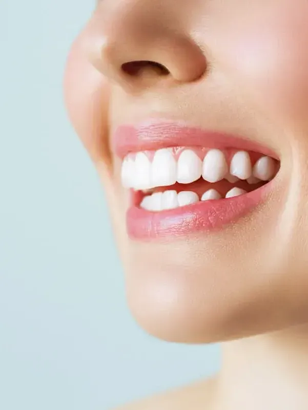 A close up of a woman 's smile with white teeth and pink lips.
