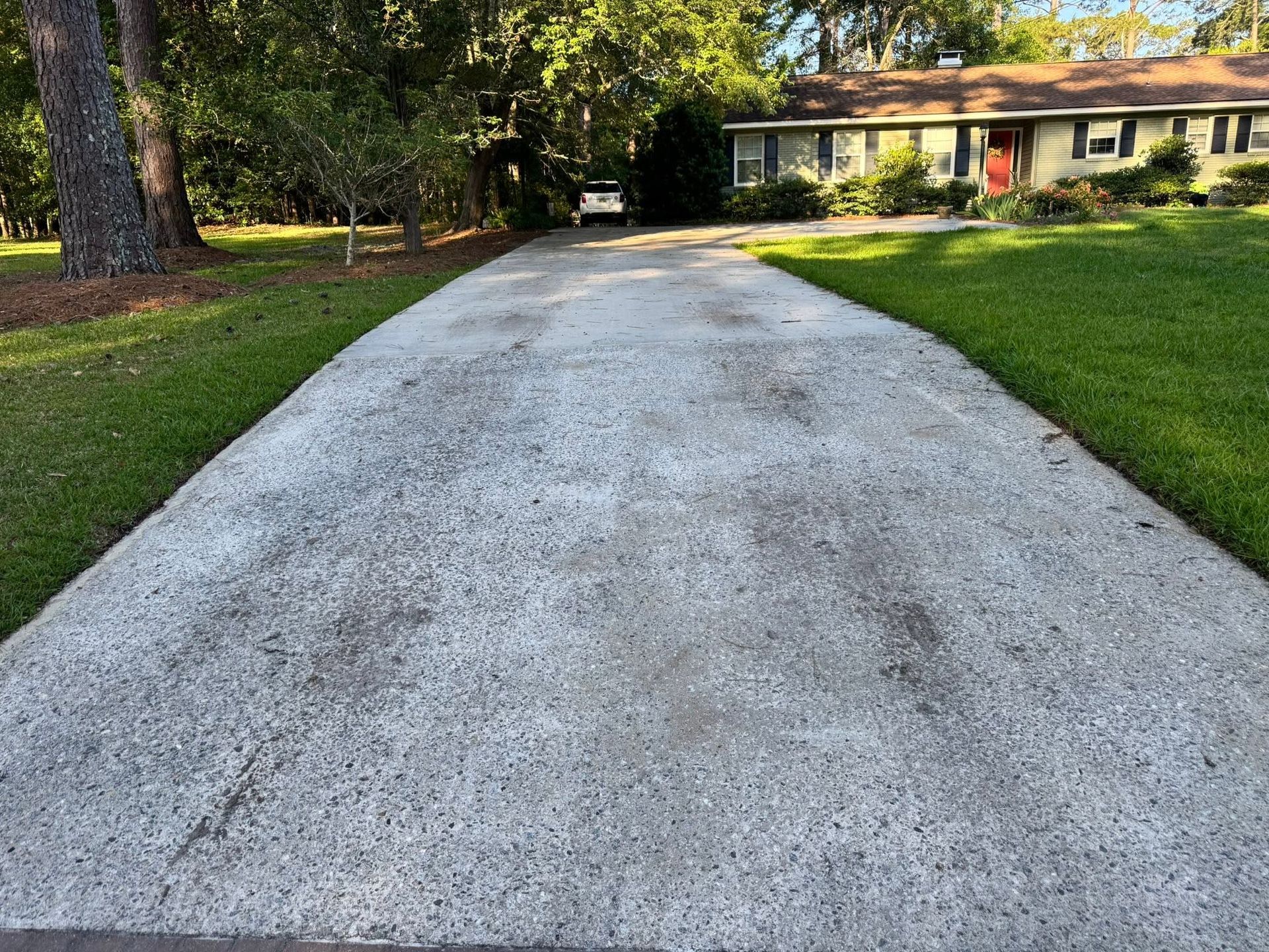 Gravel driveway leading to a house with trees and green lawn on both sides