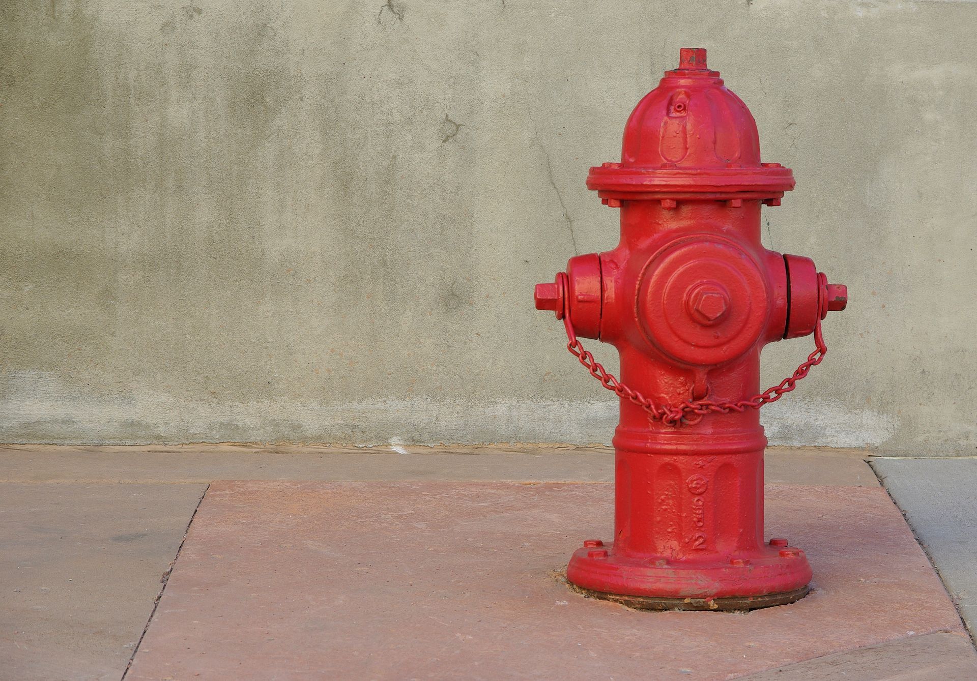 A red fire hydrant is on a lone street. A red fire hydrant is on a lone street.