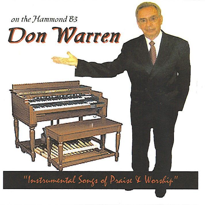 A man in a suit and tie is standing in front of an organ titled