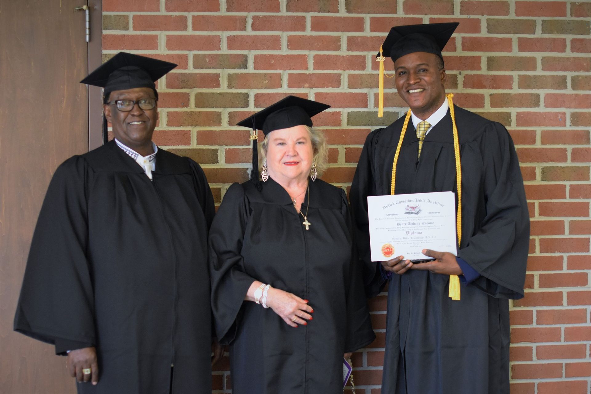 A group of graduates are posing for a picture in front of a brick wall.