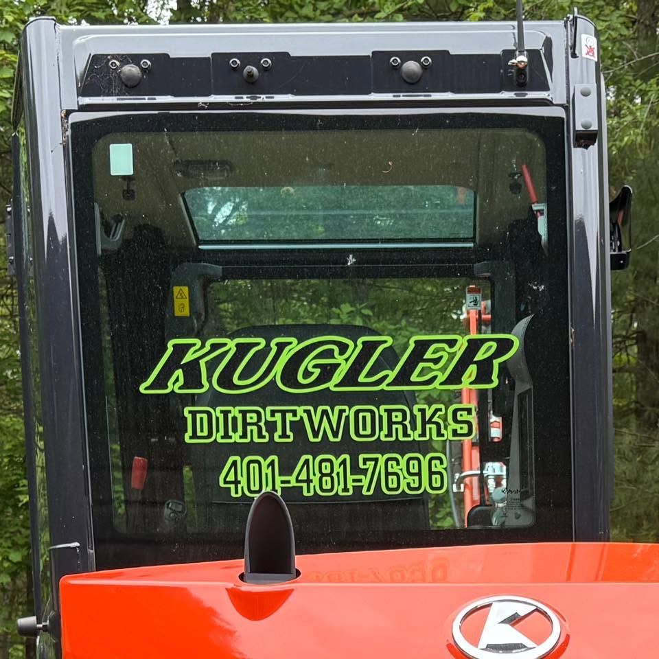 Front of a black and orange dirtwork truck with “Kugler Dirtworks” and a phone number on the windshield