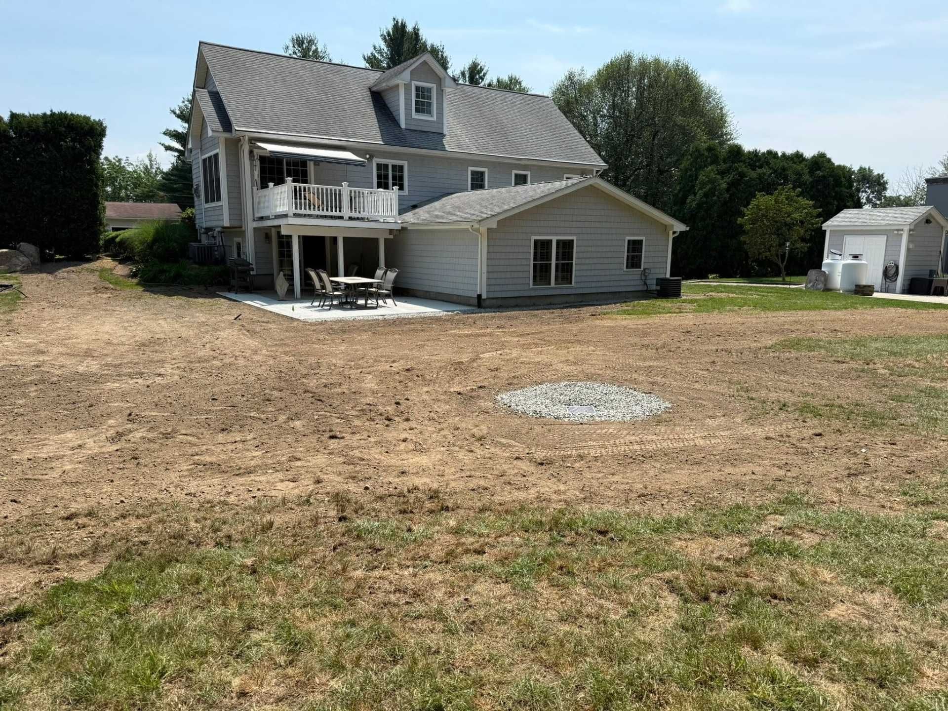 Partially damaged house with a collapsed porch, sitting on a dry, open lot under a clear sky