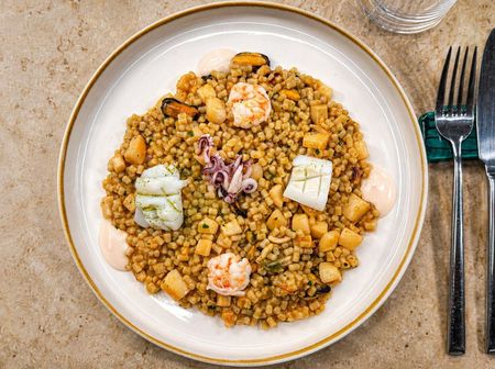 Piatto di frutti di mare: gamberi, carpaccio di pesce e tartare di tonno su un piatto blu.