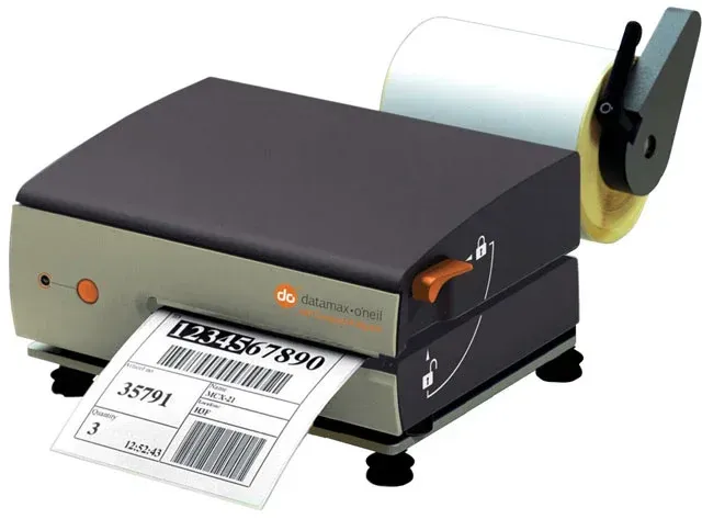 Desktop label printer printing a barcode shipping label, with label roll loaded behind it