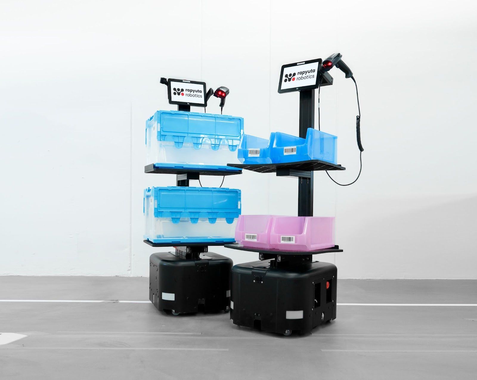 Three stacked mobile robots with blue, pink, and black bases on a white floor