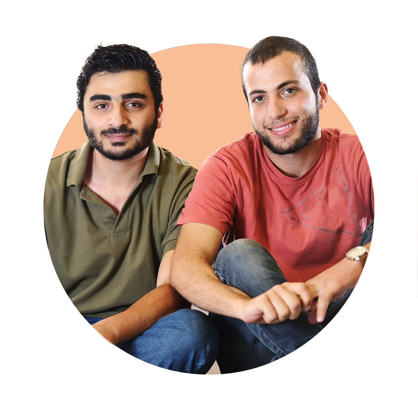 Two young males sitting down and smiling towards the camera