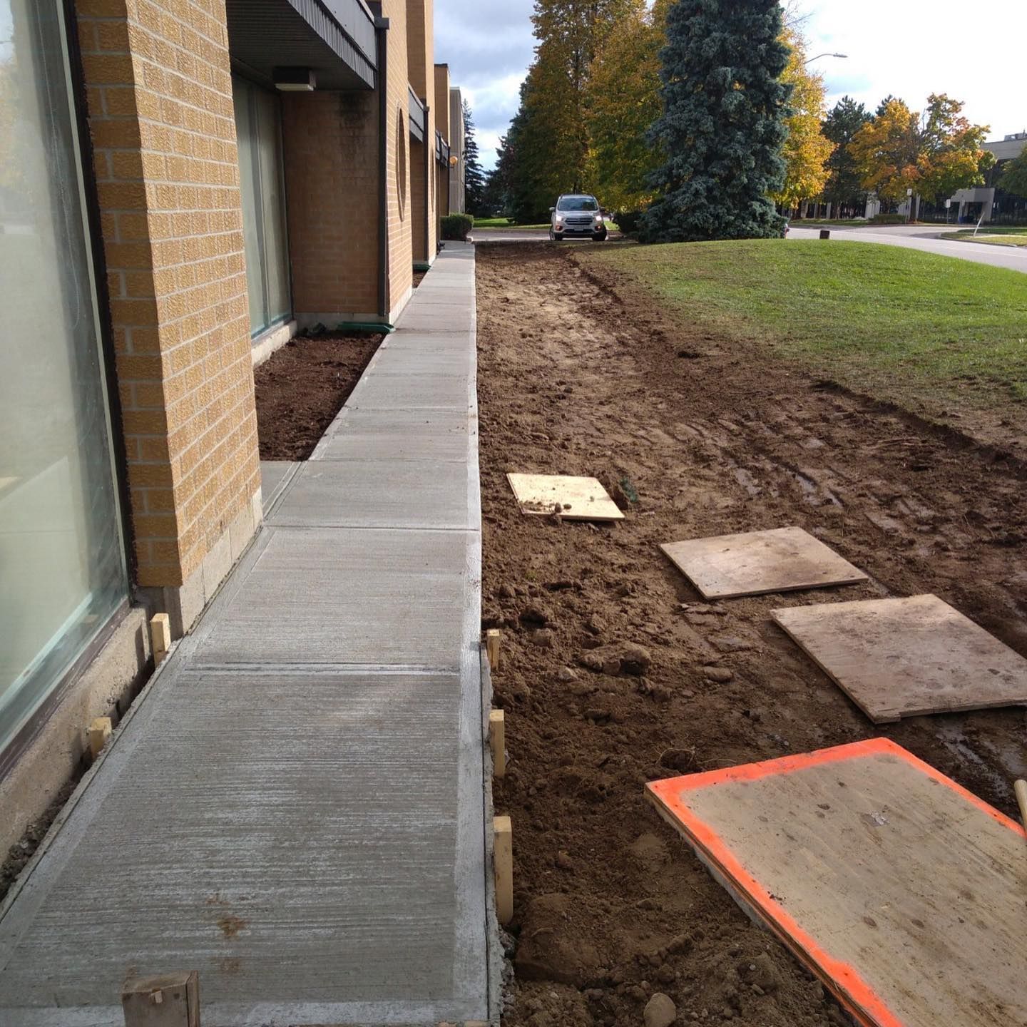 A sidewalk is being built in front of a brick building
