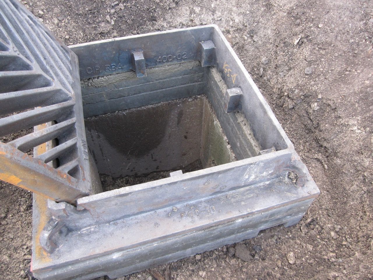 A manhole cover with the lid open is sitting on the ground.