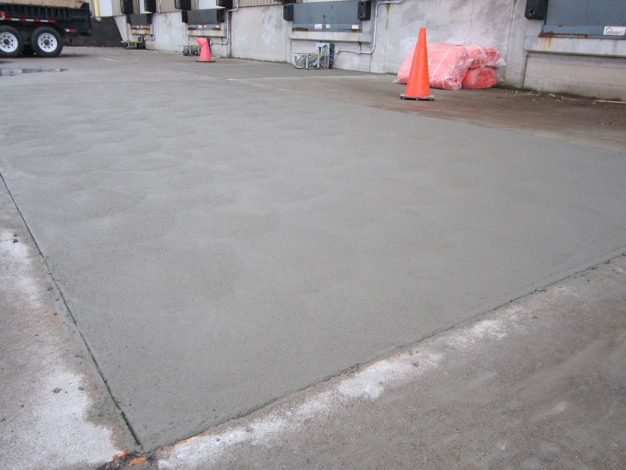 A concrete driveway with an orange cone in the middle