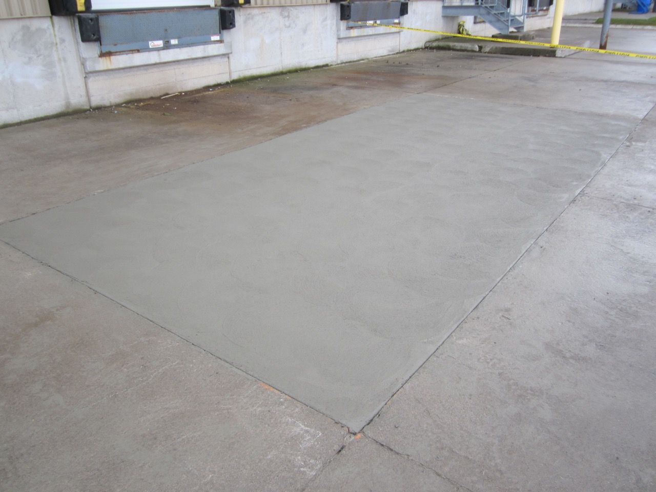 A concrete floor in front of a building with a yellow tape.