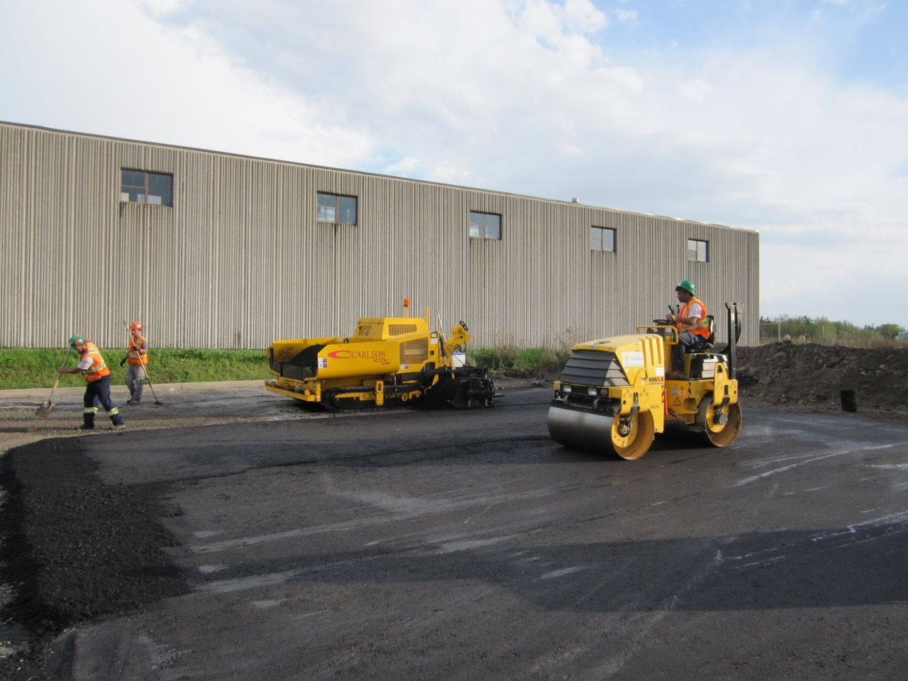 A group of construction workers are working on a road in front of a building.