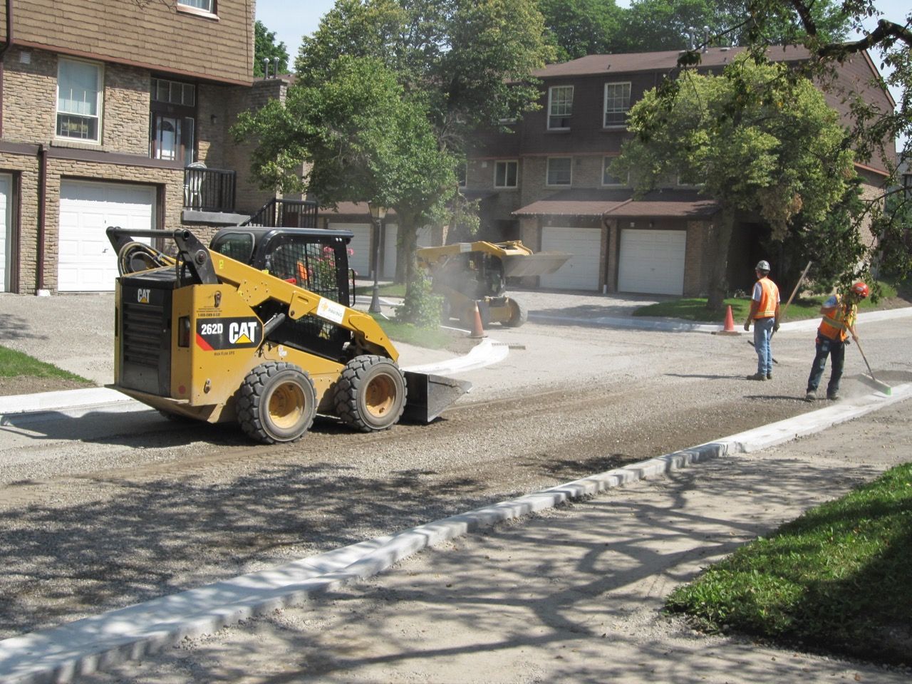 A cat skid steer is working on a street