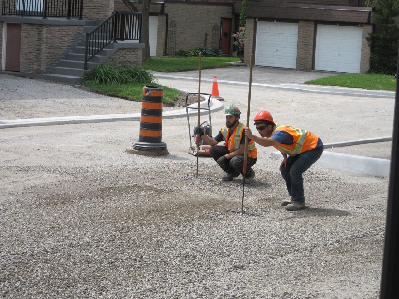 Two construction workers are squatting on a gravel road