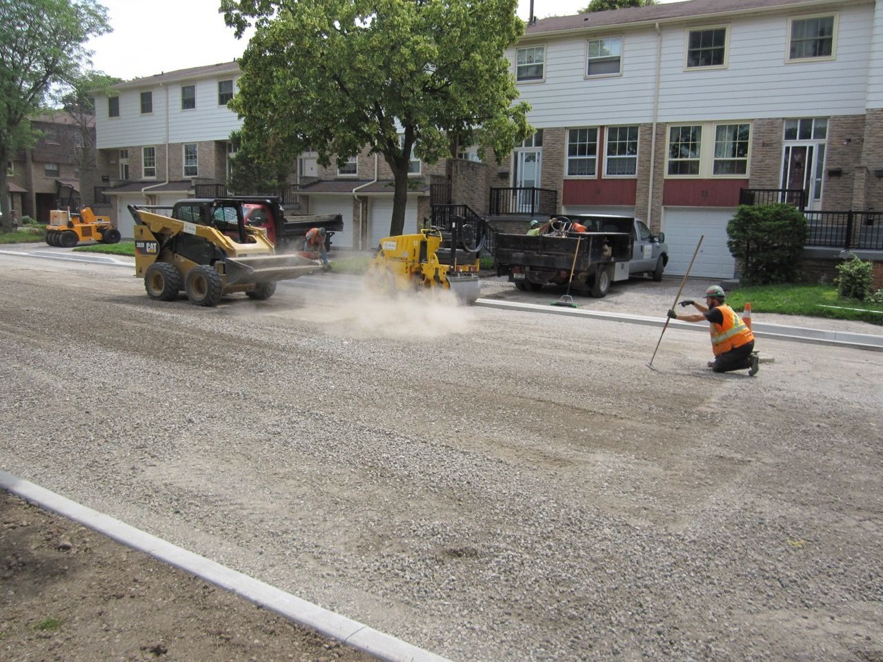 A man is kneeling down in front of a construction vehicle